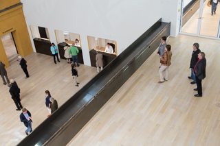 Museumshalle von oben fotografiert. Aus zwei Ebenen stehen Menschen 