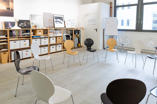 Atelier-dieSmartphotoschule <br />
Eine Frau mit langen, welligen Haaren steht mit dem Rücken zur Kamera vor einer Wand, die mit zahlreichen Fotografien bedeckt ist. Die Fotos zeigen verschiedene Szenen und Orte, die eine Vielfalt an visuellen Themen abdecken. Die Frau trägt eine helle Bluse und dunkle Hosen, während sie sich offenbar die Bilder ansieht oder sortiert. Die Szene vermittelt den Eindruck eines kreativen Arbeitsplatzes, der von visueller Inspiration geprägt ist.