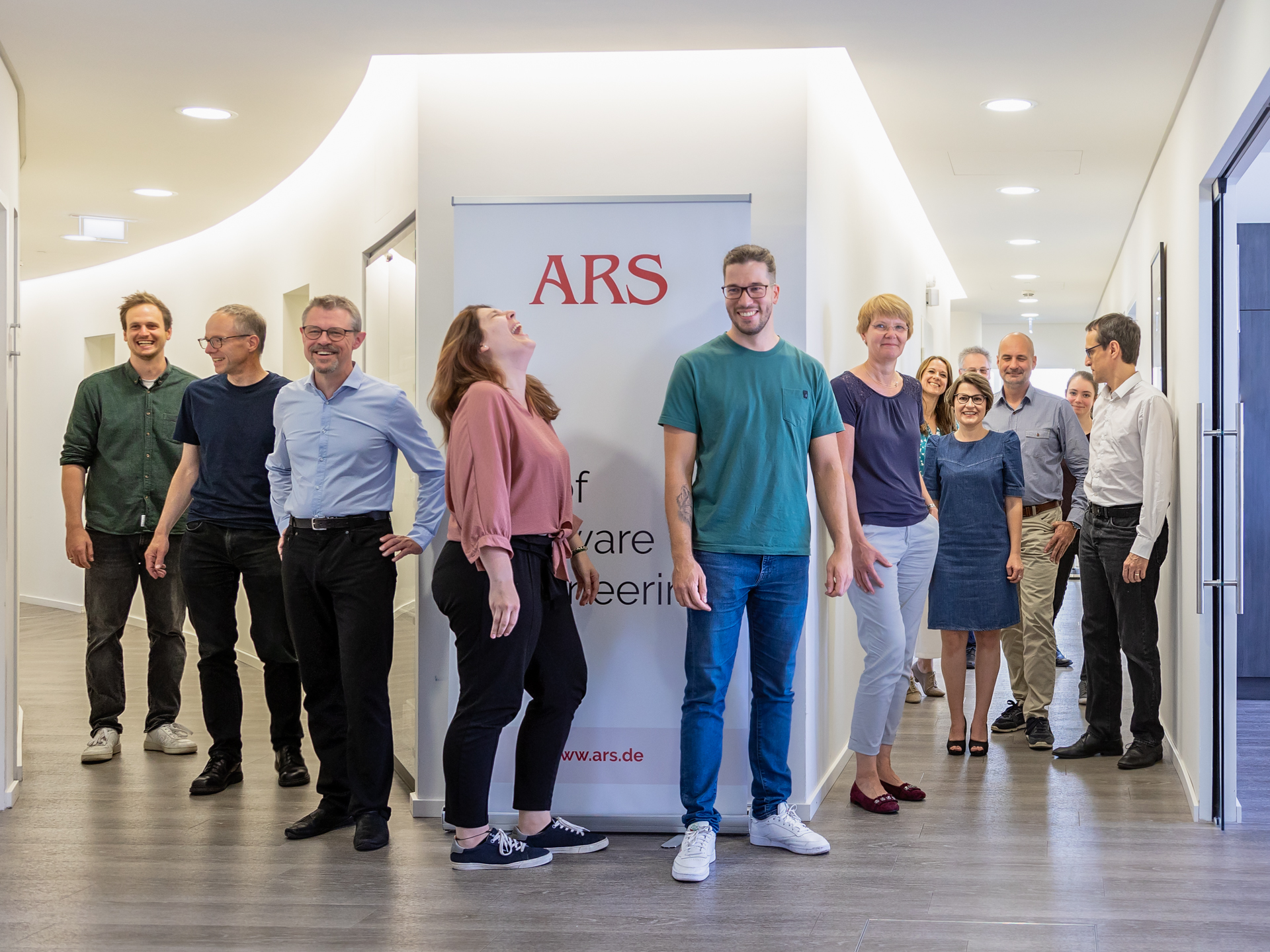 Mitarbeitende eines Unternehmens vor ARS Banner im Büro – professionelle Businessfotografie für authentische Bildsprache und starke visuelle Unternehmenskommunikation