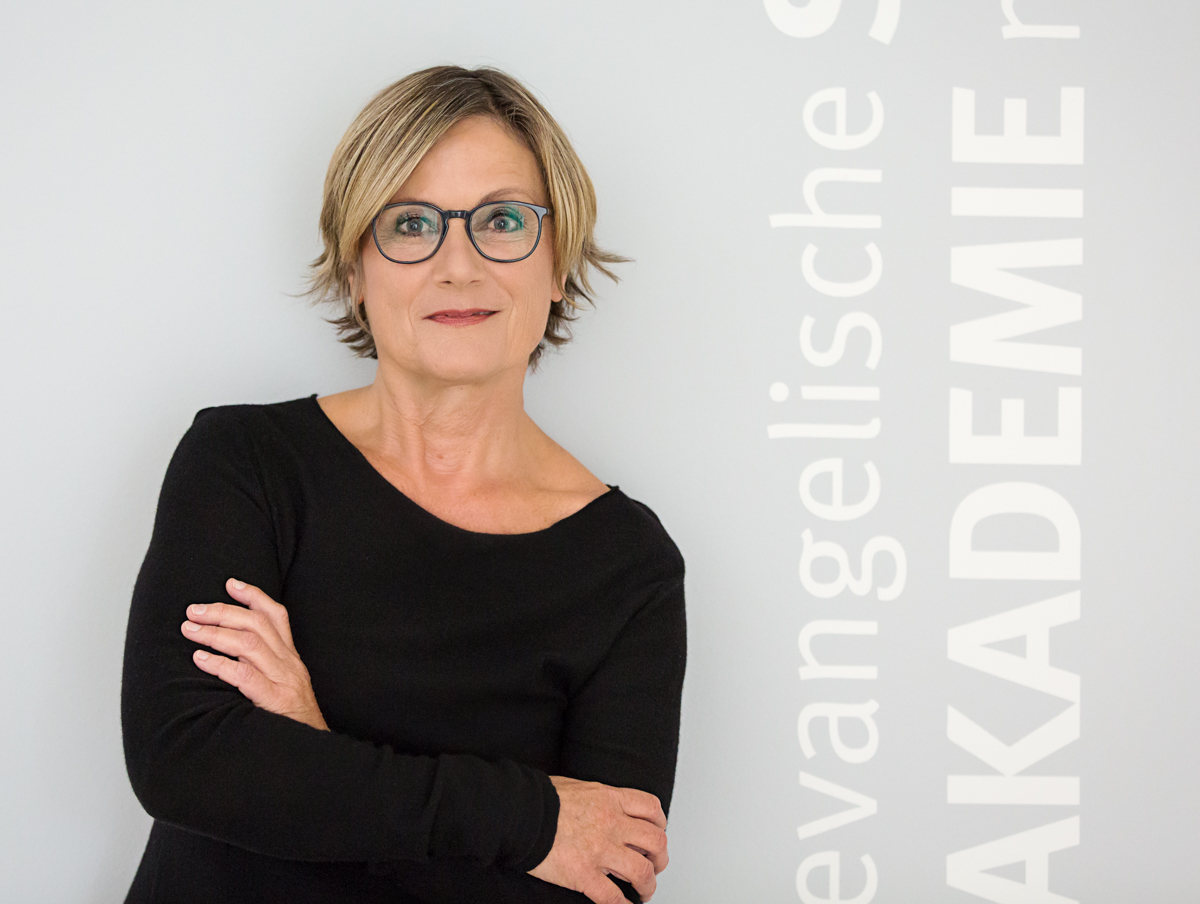 Zwei Personen im Business-Outfit besprechen gemeinsam Unterlagen an einem Tisch in einer hellen Büroumgebung.